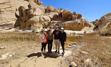 Group of hikers exploring a desert canyon with rocky formations.