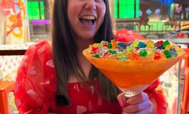 Vibrant Las Vegas scene with a woman holding a large colorful cocktail, capturing the lively Strip a.