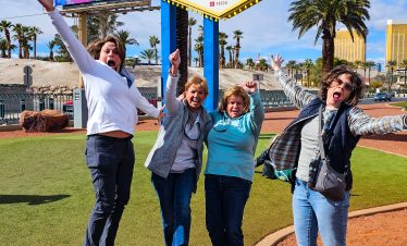 Group of friends enjoying the Las Vegas Welcome Sign at sunset, capturing fun moments in front of th.