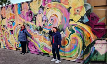 Bright mural art on Fremont Street in Las Vegas with two women taking photos.