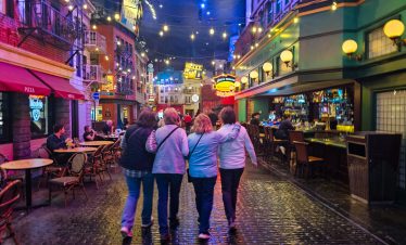 Downtown Las Vegas street scene with groups of friends enjoying vibrant nightlife and colorful light.
