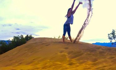 Woman throwing sand on a desert hill during sunset in Death Valley.