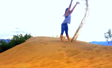 Person playing with sand in a desert landscape during a Death Valley tour.