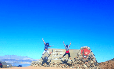 Two people jumping in front of Lake Mead sign at Lake Mead National Recreation Area.