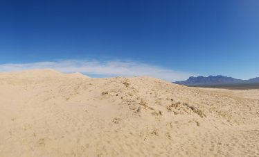 Vast desert landscape in Death Valley with sand dunes and clear blue sky.