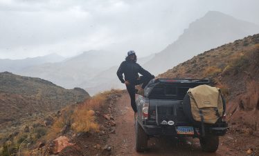 Person standing on a truck in rugged desert terrain during a Death Valley tour.