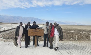 Group of tourists at Badwater Basin in Death Valley with mountains in background.