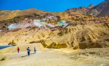 Visitors exploring the vibrant, multicolored Badlands in Death Valley during a sightseeing tour.
