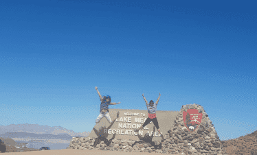 Two people jumping in front of Lake Mead sign at Lake Mead National Recreation Area.