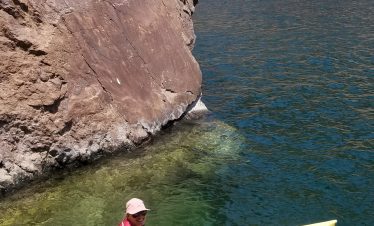 Person kayaking in Black Canyon with rocky cliffs and water.