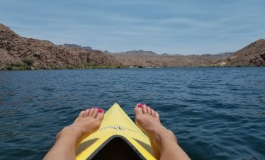 Person kayaking in Black Canyon with mountain views and blue water.