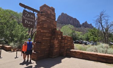 Zion National Park entrance with visitors and scenic mountain backdrop.