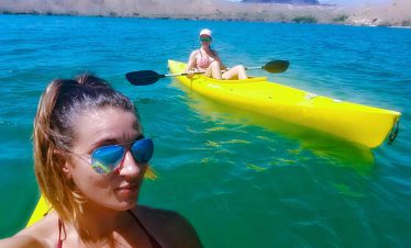 Two women kayaking on the Colorado River near Hoover Dam in bright sunlight.