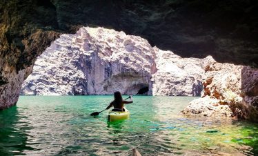 Person kayaking in Black Canyon near Hoover Dam with rocky cliffs.