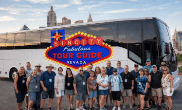 Luxury tour bus with group of tourists in front, city skyline in background, Sin City Tour Guide Nev.